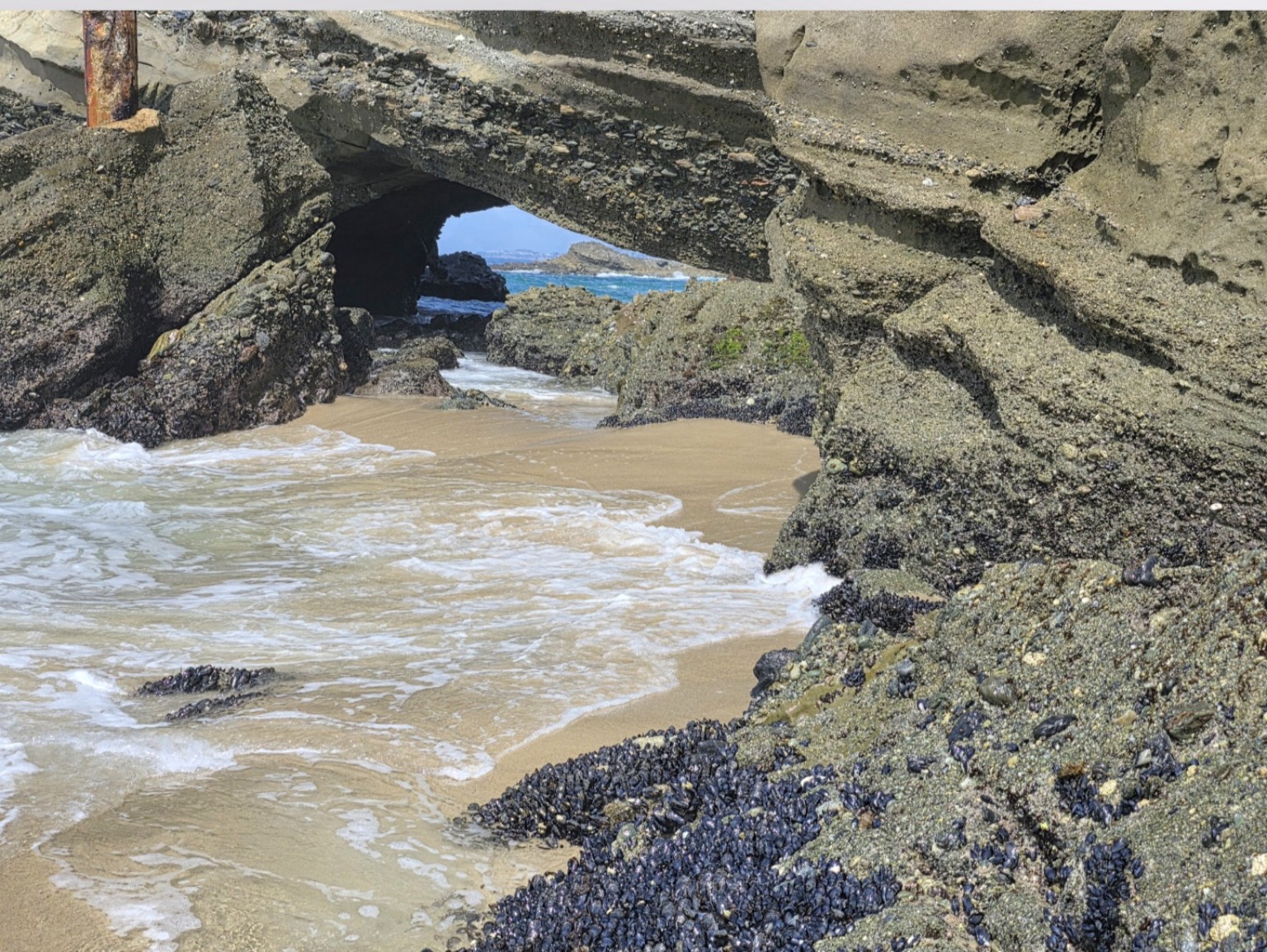 Waves entering a small cove beneath a rock arch